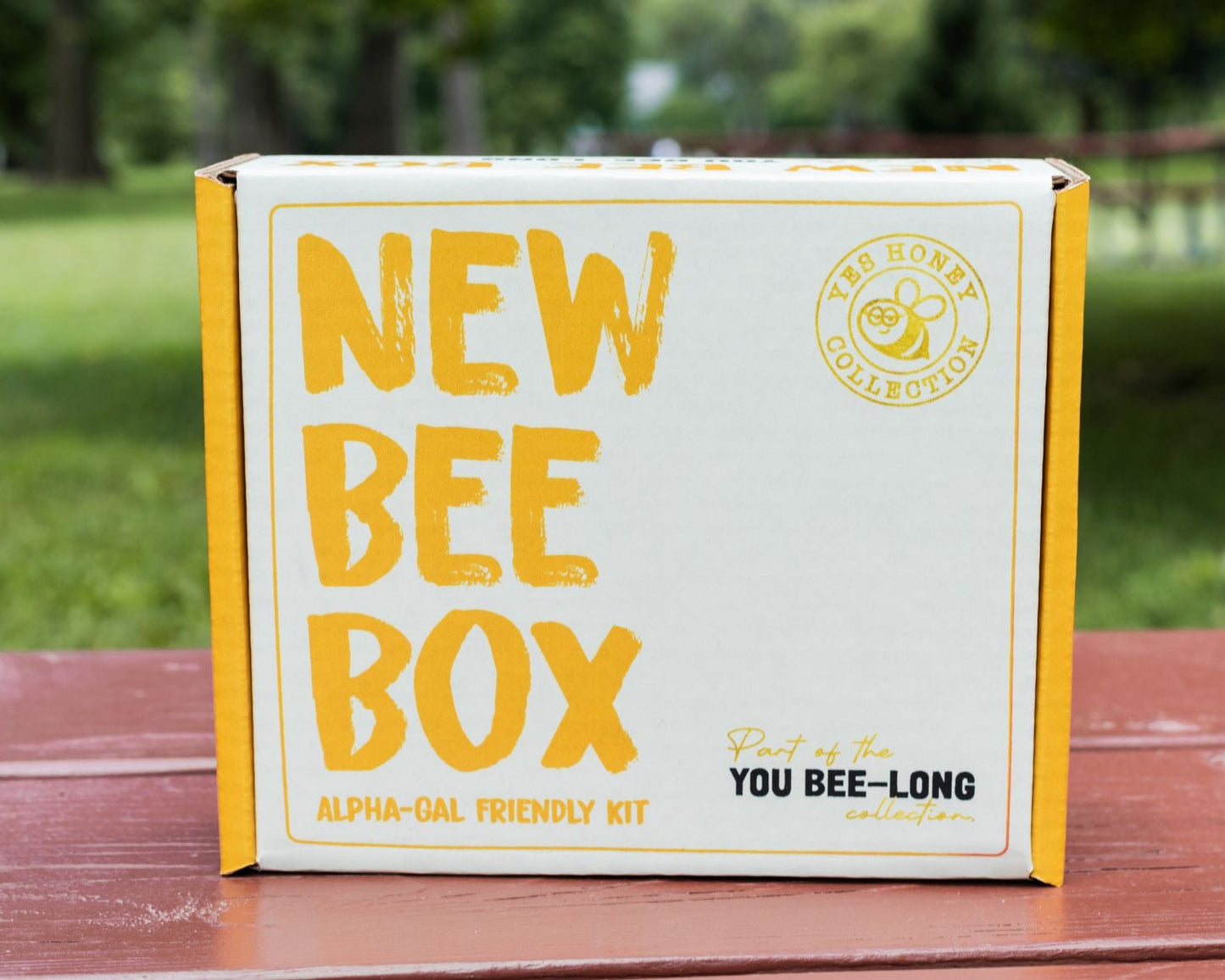 A white cardboard box that reads New Bee Box Alpha Gal Friendly Kit sits on a table 