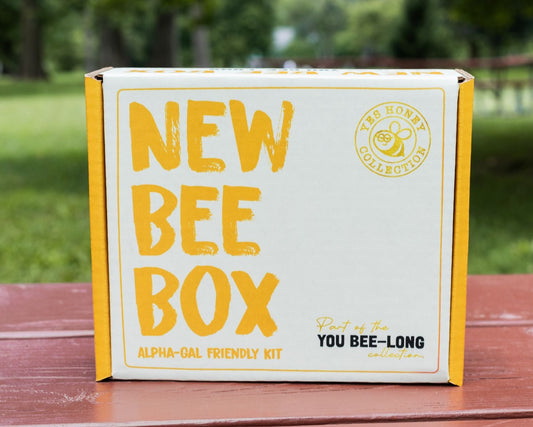 A white cardboard box that reads New Bee Box Alpha Gal Friendly Kit sits on a table 